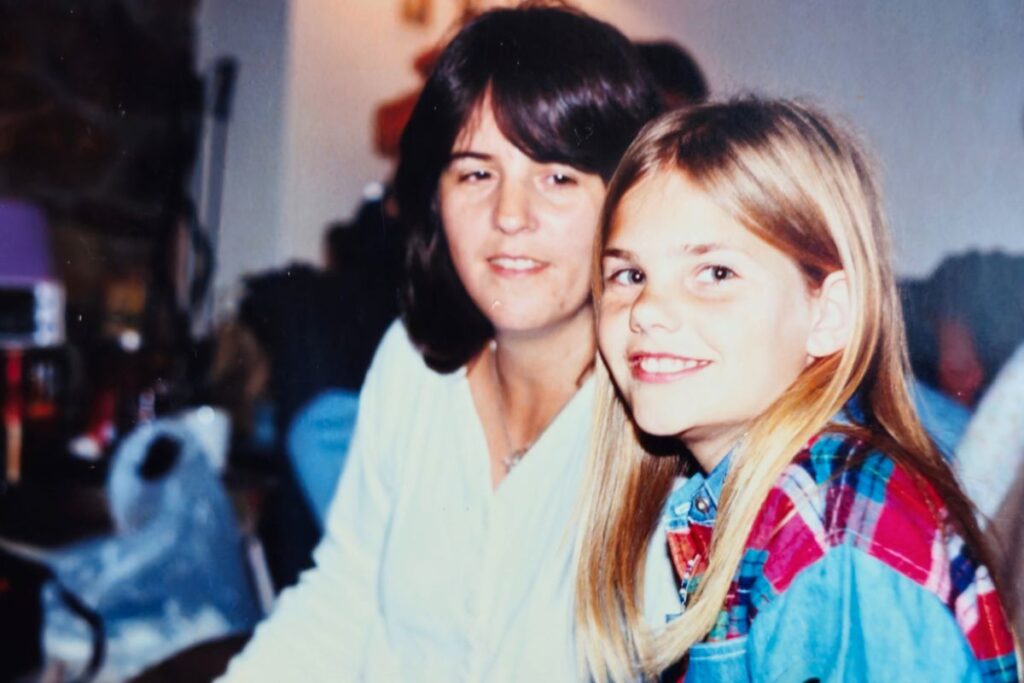 Me with my Mom at my aunt and uncle's house. I am in front smiling at the camera, and my mom is behind me looking at me.