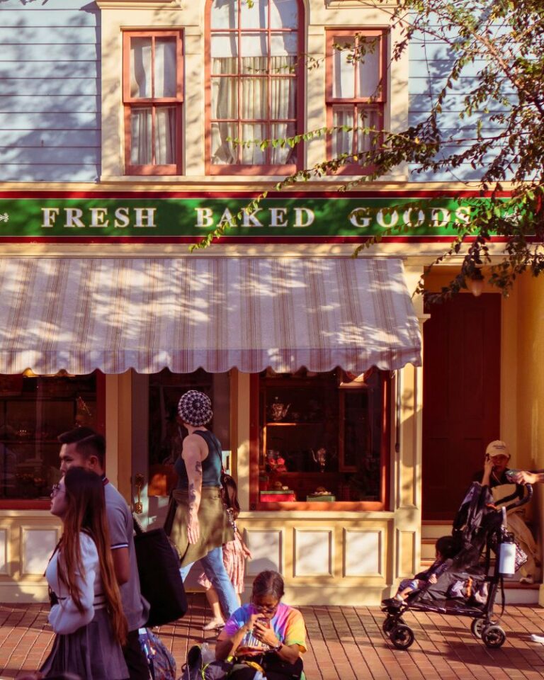 A photo of a group of people walking past a bakery in Disneyland.