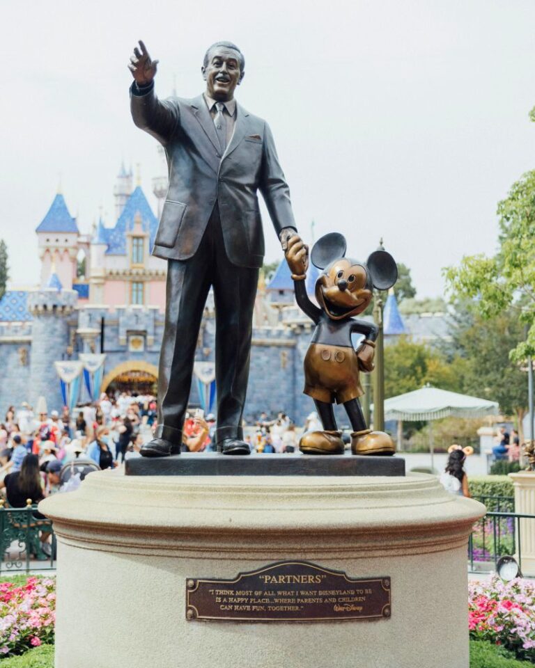 A photo of a statue of Walt Disney and Mickey Mouse holding hands cast in bronze.