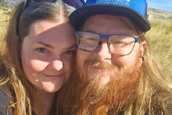 My Rock A man and woman with long hair, smiling outdoors in the sunshine.
